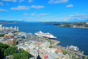 Aerial view of a vibrant waterfront with cruise ships, colorful buildings, and a clear blue sky reflecting over calm waters.