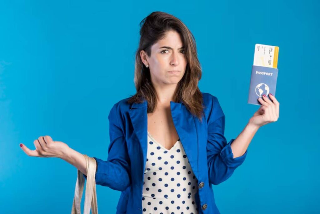 A woman in a blue blazer and polka-dot shirt holds a passport and a travel itinerary against a bright blue background.