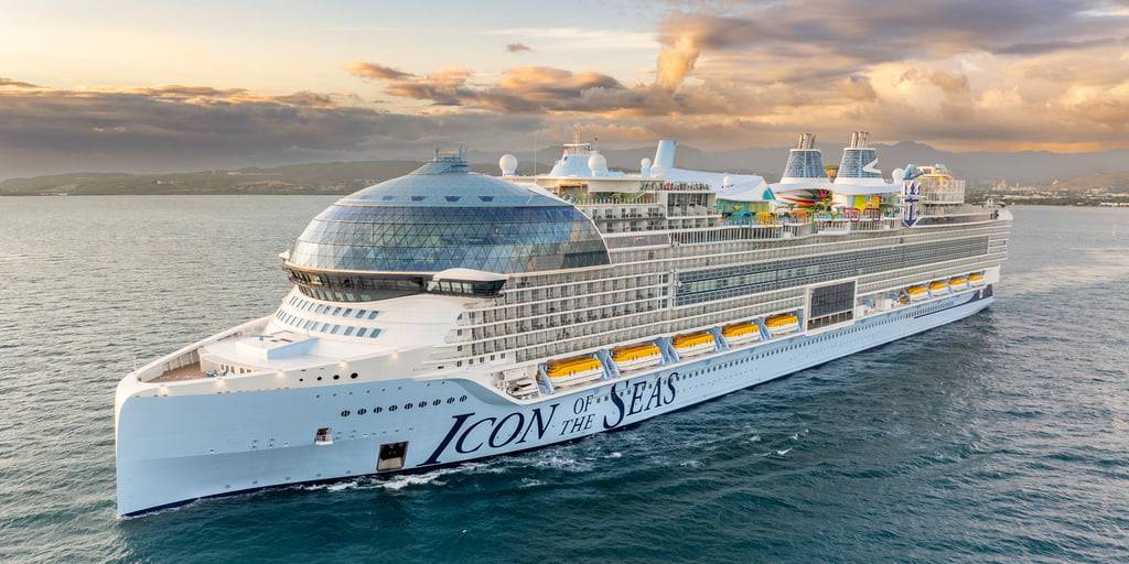 The Icon of the Seas, a large cruise ship, sails through calm waters under a cloudy sky, showcasing its modern design.