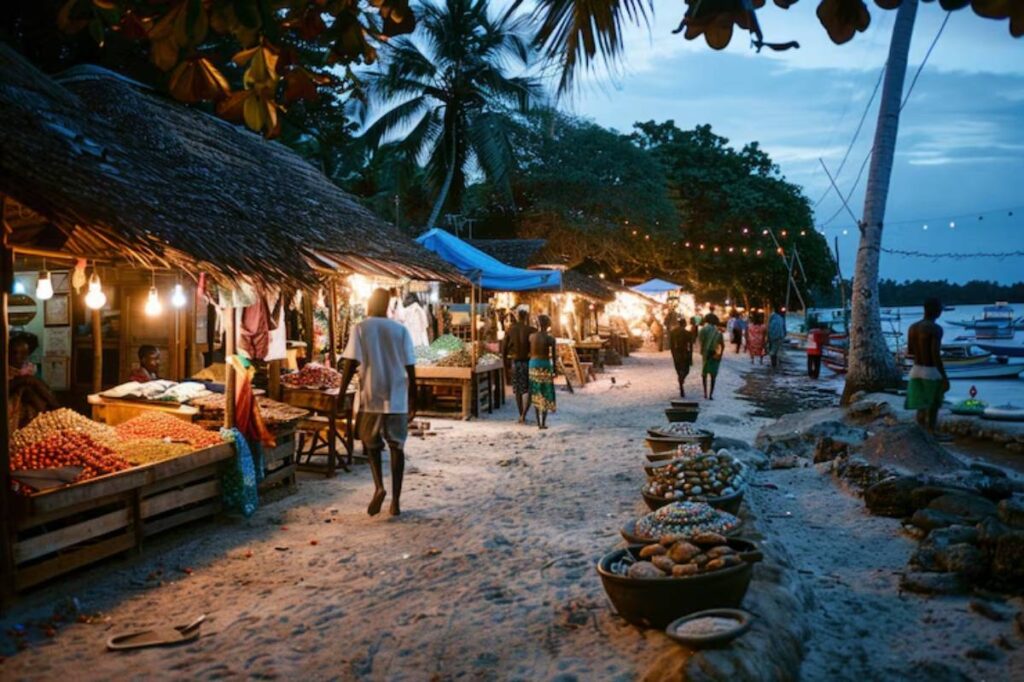 A bustling beach market at dusk, lined with illuminated stalls selling fruits and goods, with palm trees and a tranquil sea in the background.