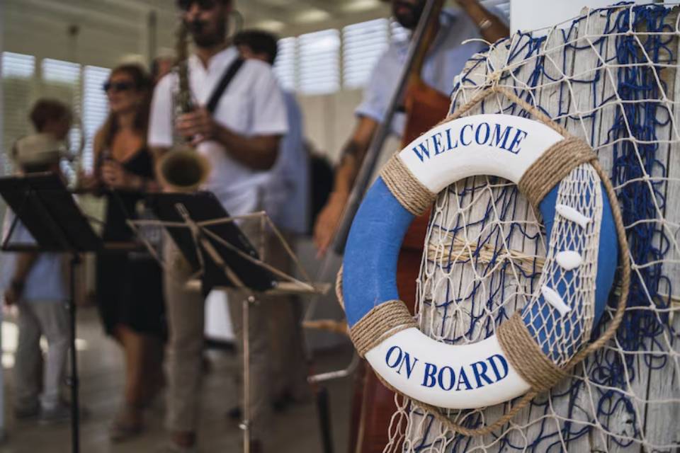 A nautical-themed welcome sign hangs beside a lively band playing instruments in a bright, festive indoor setting.