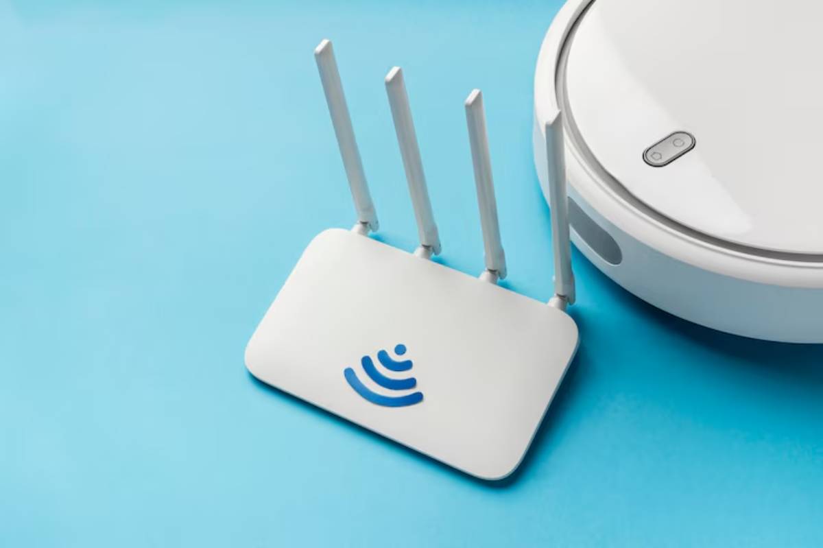 A white Wi-Fi router with four antennas sits next to a round robotic vacuum on a blue background.